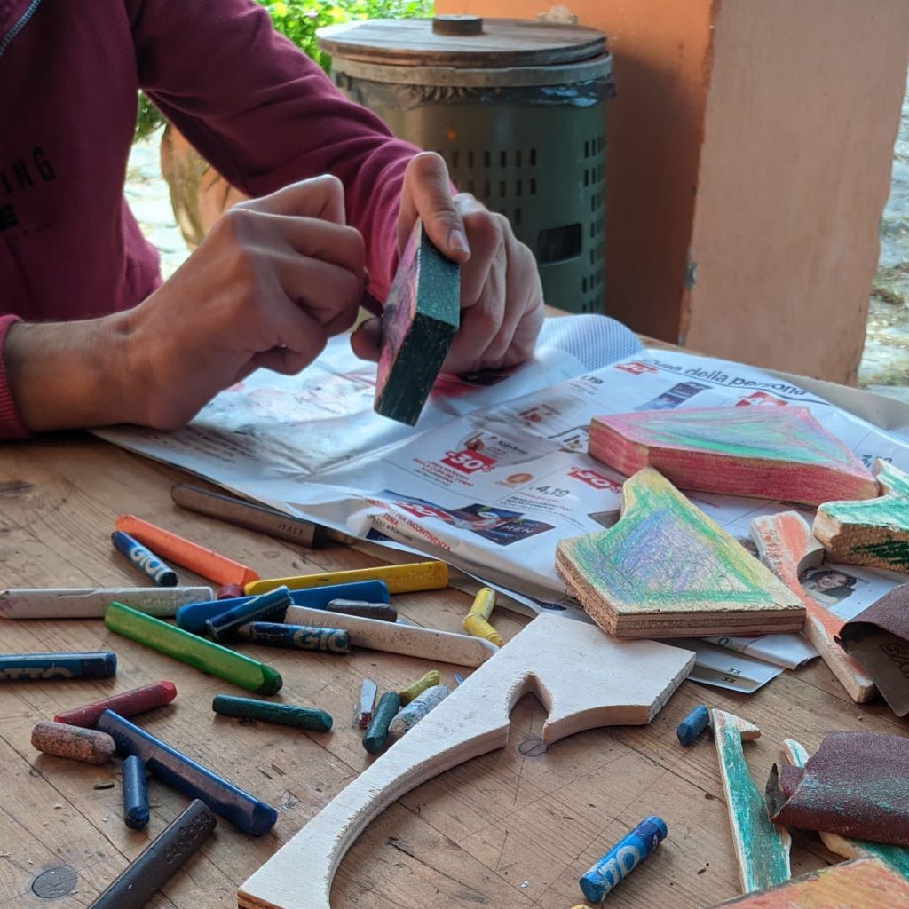 Dettaglio di mani che colorano un pezzo di legno di un'opera collettiva