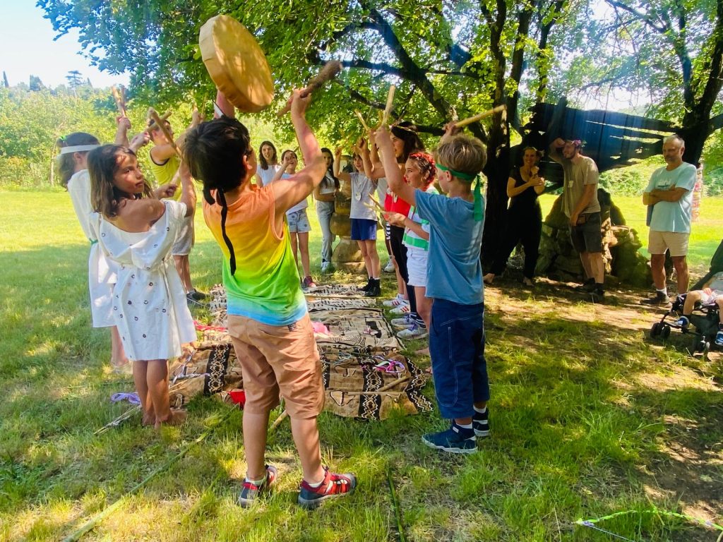 Bambini e bambine in cerchio durante un'attività dei centri estivi a Le Rose