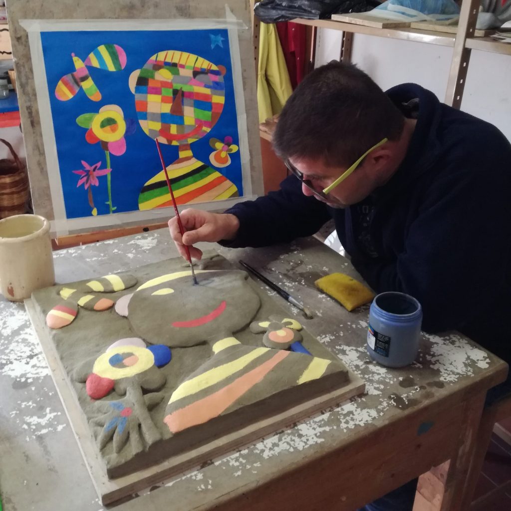 Damiano mentre colora una delle sue opere in ceramica